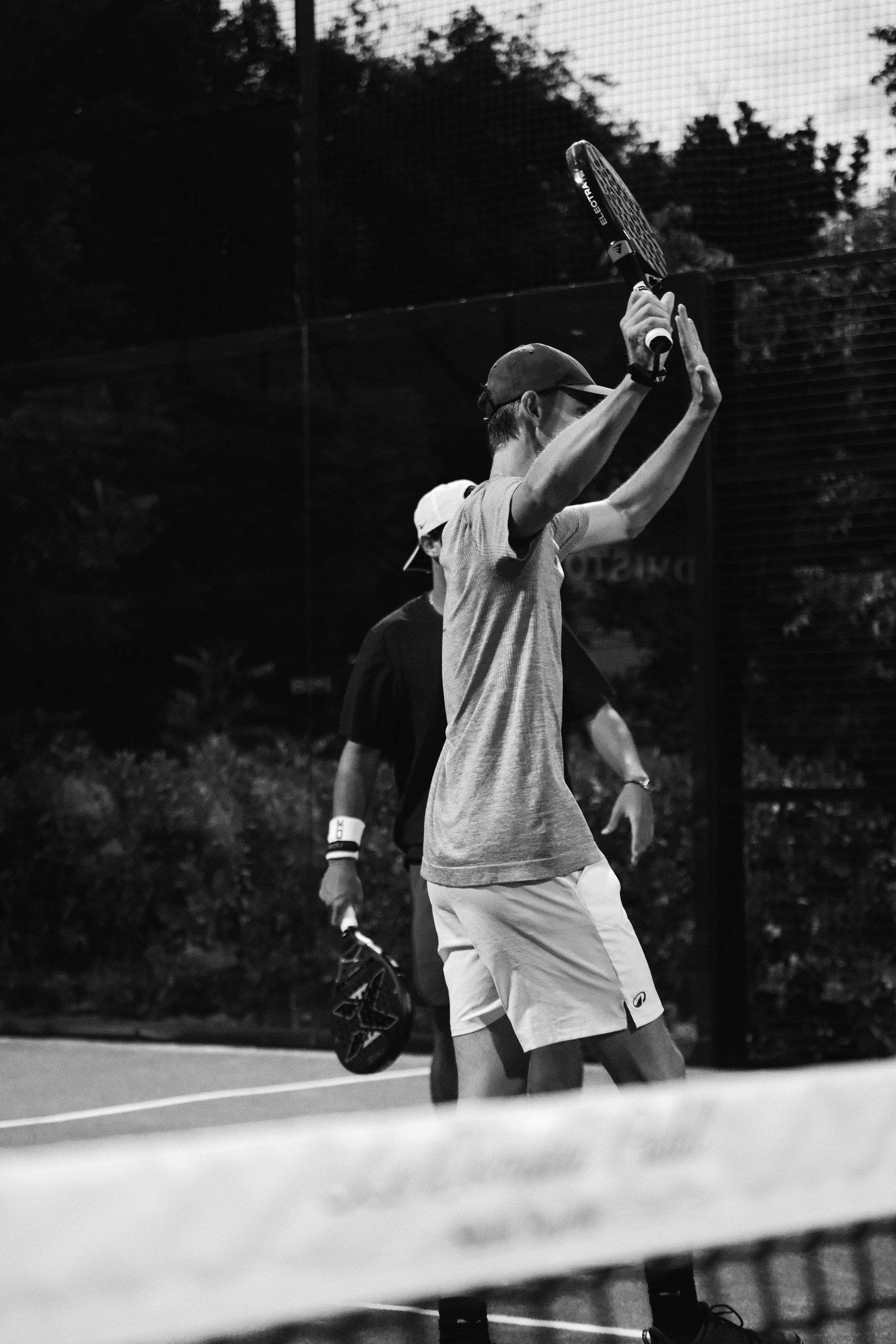 A player raising his racket on court at Le Domaine, in black and white